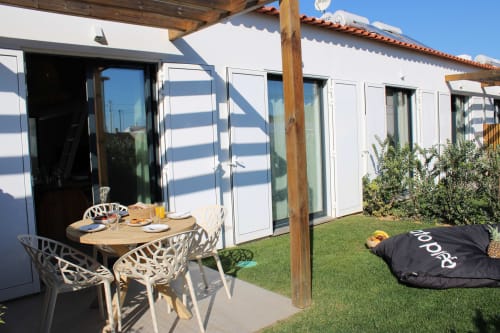 Pátio da villa Casa Cordoama com mesa de jantar, vista para o oceano, jardim verdejante e arquitetura moderna branca em Bordeira.