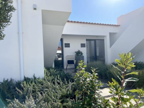 Entrada da villa Casa Cordoama com arquitetura moderna branca, jardim privado com plantas verdes e área de estar em Bordeira