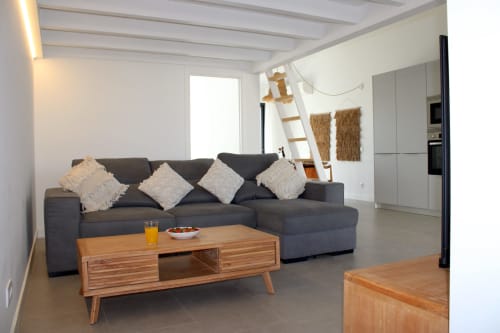 Sala de estar moderna da villa Casa Cordoama em Bordeira com sofá cinzento, móveis em madeira e acesso à vista de mar