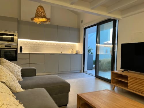 Espaçosa sala de estar integrada na villa Casa Cordoama com cozinha cinza, vistas para o mar através de portas envidraçadas e costa de Bordeira