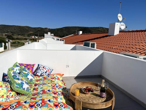 Cama colorida no terraço da cobertura da villa Casa Cordoama em Bordeira com vista para o mar e espaço para refeições