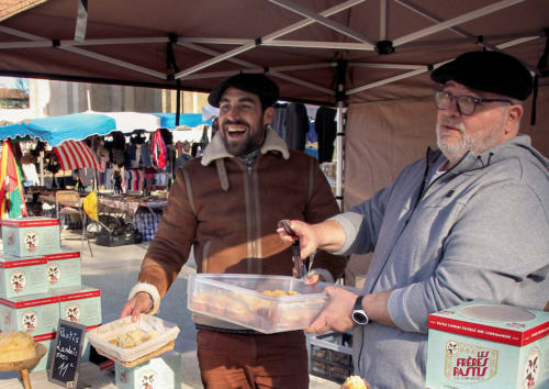 Twee mannen delen eten bij een openluchtmarktstand in de buurt van Baccara Lodge in Arengosse, Frankrijk