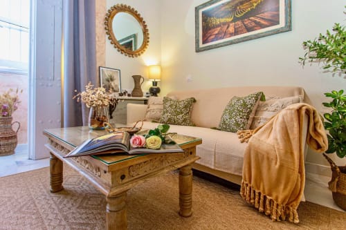 Elegante sala de estar en apartamento de Puerto Santa María con sofá beige, mesa de centro de madera y espejos decorativos