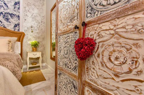 Elegante dormitorio con puerta de madera tallada ornamentada, decoración de corazón de rosa roja y papel tapiz de patrón azul y blanco en Wehost