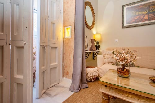 Elegante pasillo de apartamento en Puerto Santa María con puertas blancas, espejo ornamental, iluminación cálida y zona de descanso