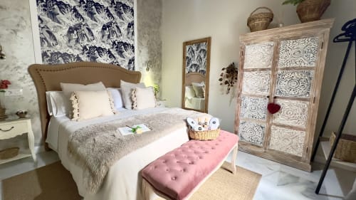 Dormitorio elegante en Wehost Costaluz de Puerto Santa María con cabecero tapizado, ropa de cama neutra, banco rosa y