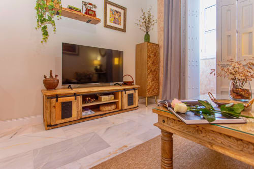 Sala moderna con mueble de TV de madera, televisor de pantalla plana, muebles de madera y plantas decorativas en Puerto Santa María