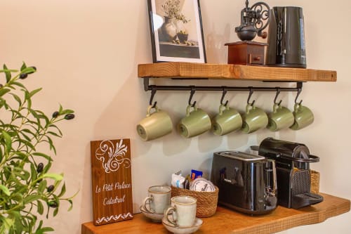 Estantes de cocina de madera con tazas verdes colgantes, cafeteras y artículos decorativos en apartamento de Puerto Santa María
