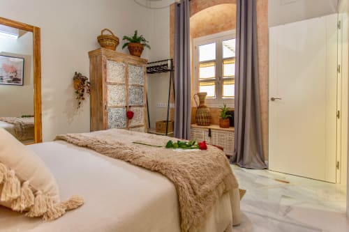 Elegante habitación en Casa Guayaba, Puerto Santa María, con ropa de cama blanca, muebles tejidos y comodidades modernas