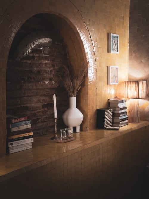 Coin de lecture douillet au Riad Les Lauriers Blancs à Marrakech avec alcôve voûtée, vase blanc, livres et éclairage chaleureux
