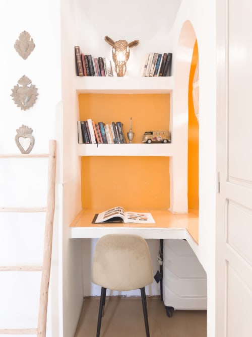 Petit espace de travail moderne au Riad Les Lauriers Blancs à Marrakech avec murs orange, bureau, chaise crème et étagère flottante