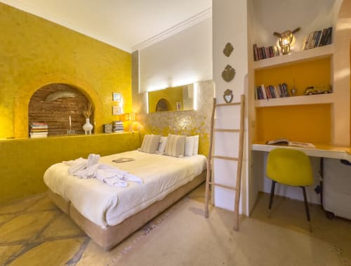 Chambre jaune éclatante du Riad Les Lauriers Blancs à Marrakech avec literie blanche, alcôve intégrée, bureau et étagères