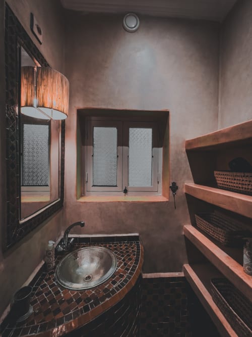 Salle de bains du Riad Les Lauriers Blancs à Marrakech avec carrelage en terre cuite, lavabo rond et fenêtre