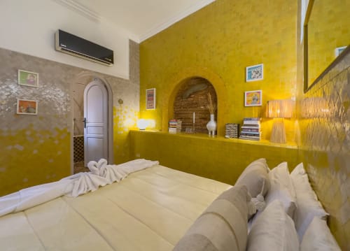 Chambre jaune éclatante au Riad Les Lauriers Blancs à Marrakech avec literie blanche, niche voûtée et climatisation