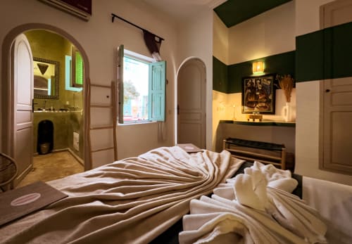 Jade room at Riad Les Lauriers Blancs in Marrakech with bed, arched bathroom, window, and dark green accent wall