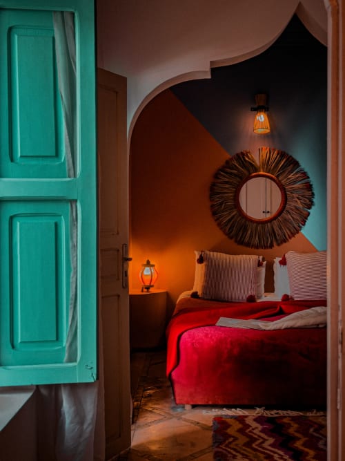 Ruby room at Riad Les Lauriers Blancs, Marrakech: vibrant red bed with turquoise door and ornate circular mirror