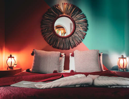 Chambre Ruby du Riad Les Lauriers Blancs à Marrakech avec un lit luxueux aux oreillers rayés, miroir rond et ambiance chaleureuse