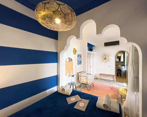 Chambre Saphir au Riad Les Lauriers Blancs à Marrakech avec murs rayés bleus, lustre doré ouvragé et style marocain