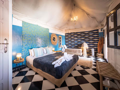 Chambre turquoise au Riad Les Lauriers Blancs à Marrakech avec murs à motifs bleus, lit en bois, carrelage à damier et élégante