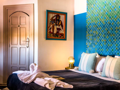 Chambre turquoise au Riad Les Lauriers Blancs à Marrakech avec mur d'accent motifs, porte en bois et coussins décoratifs