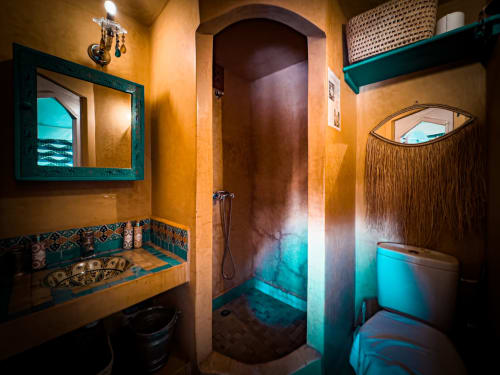 Salle de bain turquoise du Riad Les Lauriers Blancs à Marrakech, avec accents bleu canard, douche voûtée et miroir décoratif