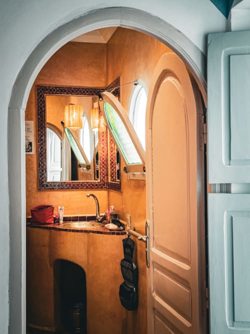 Salle de bain Amber au Riad Les Lauriers Blancs, Marrakech avec murs en terre cuite et porte voûtée