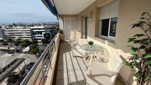Sunny balcony at Marbella Home Rentals Marina Banús apartment with sea views, white furniture, and potted plants