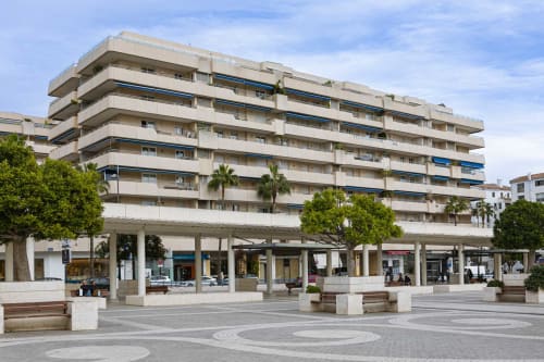 Modern beachfront apartment building in Puerto Banús, Marbella with retail spaces, balconies, and sea views