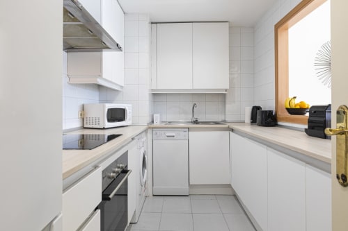 Modern kitchen in Marina Banús apartment with white cabinetry, stainless steel appliances, and light wood countertops