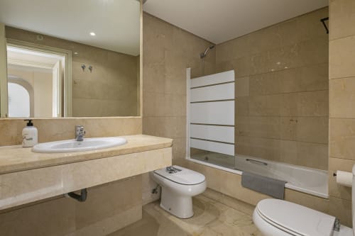 Luxurious marble bathroom in Marina Banús apartment with vanity, bidet, and glass shower enclosure