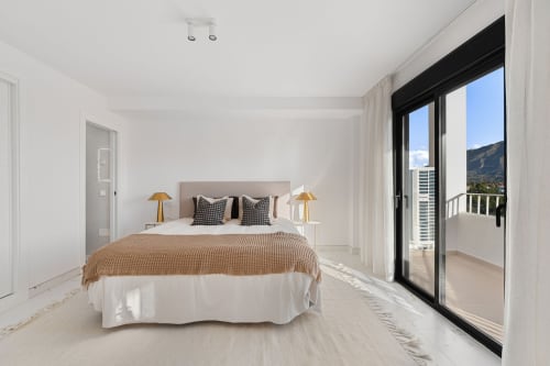 Bright modern bedroom in Marbella apartment with mountain views, king bed, terrace access, and contemporary furnishings