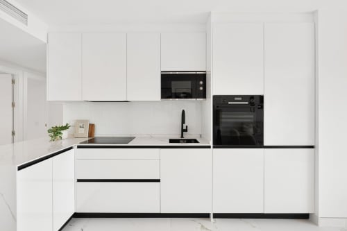 Modern white kitchen with black countertops and appliances in Marbella luxury apartment rental