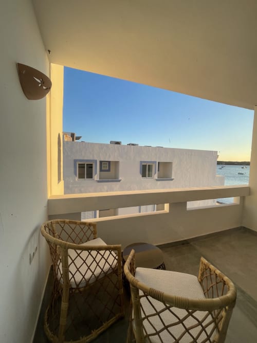 Estudio Formentera Especial Luna con sillas de ratán en balcón con vistas a edificios encalados y mar en La Savina