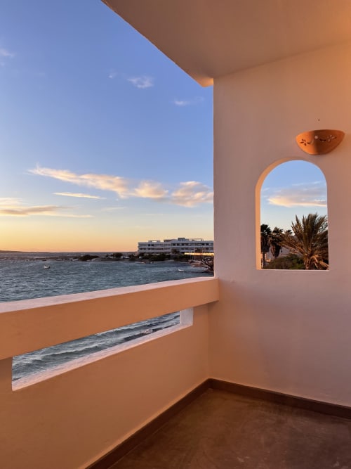 Vista del balcón de Luna Studio en Formentera Especial, La Savina, con vistas al mar, ventana arqueada y cielo al atardecer