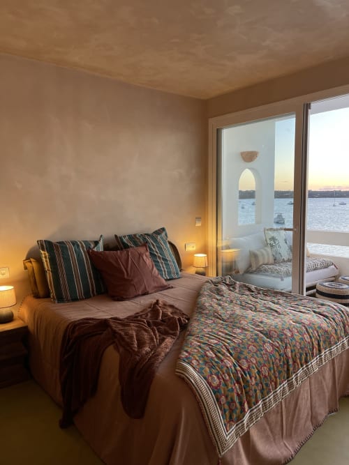 Dormitorio Luna con almohadas rayas y vistas al mar a través de puertas de cristal que dan al agua en el hotel Formentera Especial.