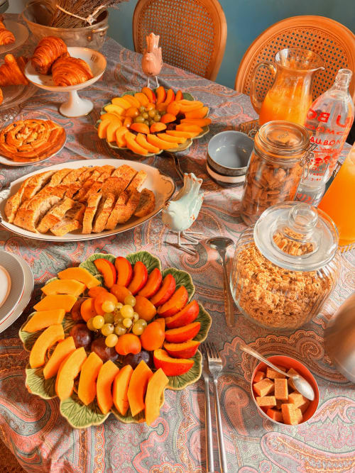 Table de petit-déjeuner élégante au château de Grignan avec buffet aux teintes orangées : croissants, fruits frais et