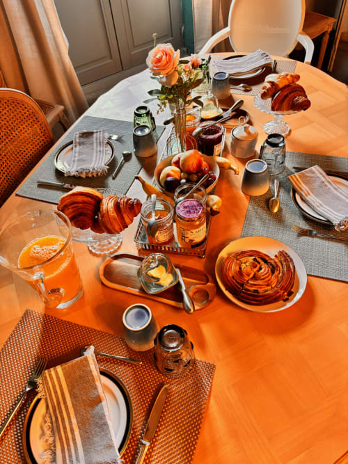 Petit-déjeuner raffiné au B&B La vie de château à Grignan avec croissants, fruits frais et jus d'orange