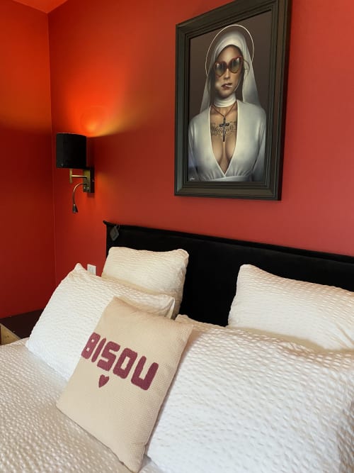 Chambre élégante chez Lady Jule aux murs rouges, oreillers crème et portrait encadré au-dessus du lit noir