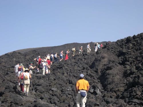 Escursionisti che percorrono i pendii vulcanici vicino all'Hotel Milomax a Milo, Monte Etna, Sicilia