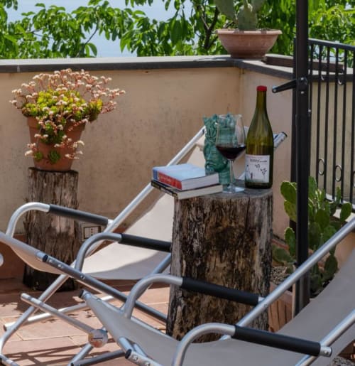 Terrazza sul tetto dell'Hotel Milomax a Milo con lettini, vino e piante fiorite che si affacciano sulla campagna.