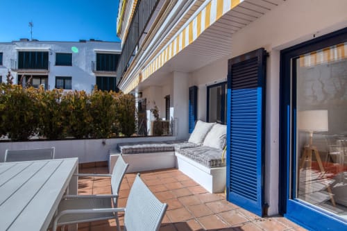 Beachfront apartment terrace in Palafrugell with seating, blue shutters, and sea views