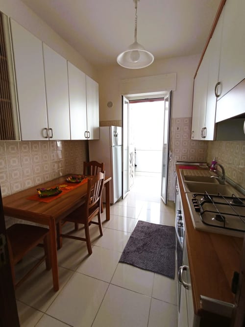 Cucina moderna in Casa Vacanze Alba, appartamento a Bari con zona pranzo, fornello a gas e accesso al balcone con vista mare