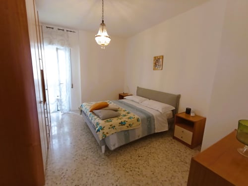 Camera luminosa a Casa Vacanze Alba a Bari con letto matrimoniale, mobili in legno e illuminazione con lampade a sospensione