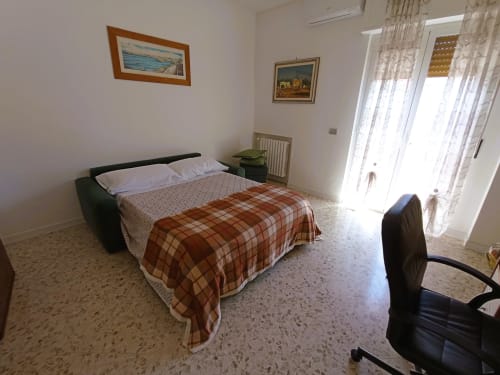 Camera luminosa a Casa Vacanze Alba a Bari con letto matrimoniale, mobili in legno e accesso al balcone con vista mare