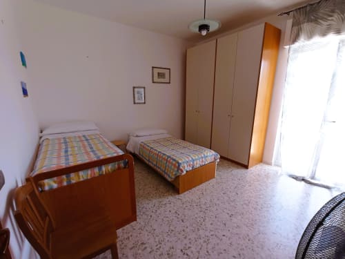 Spaziosa camera da letto a Casa Vacanze Alba a Bari con due letti singoli, armadi in legno e accesso al balcone con vista sul mare