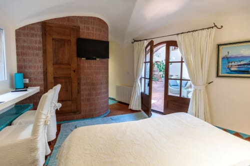 Spacieuse chambre double à Villa Marina Di Cavu à Bonifacio avec vue sur le jardin, lit blanc, armoire en bois, TV et