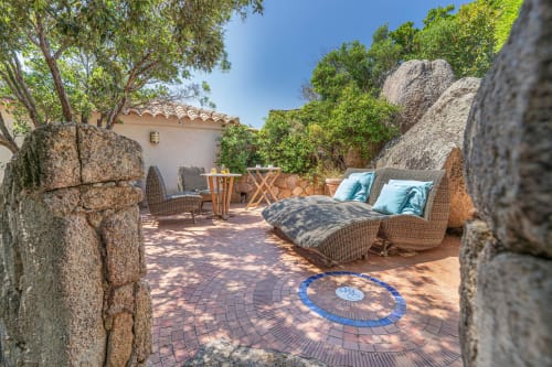 Patio de villa côtière avec chaises longues, murs en pierre et jardin méditerranéen à Villa Marina Di Cavu, Bonifacio