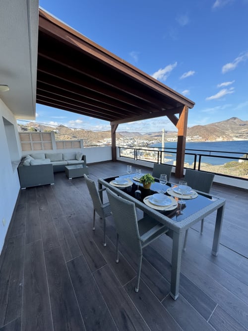 Terraza de lujo en El Faro De Los Genoveses con mesa de comedor, zona de descanso y vistas panorámicas al mar sobre San José, Almería