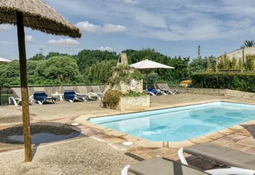 Área de piscina Can Gat Vell con tumbonas, sombrilla blanca y refugio techado en Gerona, Cataluña