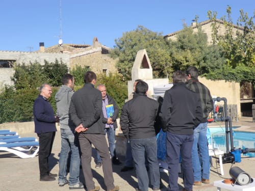Grupo reunido en el área de piscina de Can Gat Vell en Girona, Empordà-Catalunya, con edificios de piedra y vegetación visible